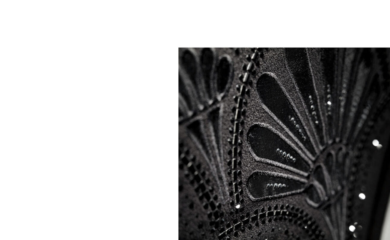 Close-up of a black, intricately decorated fabric with floral patterns by La Parisienne.