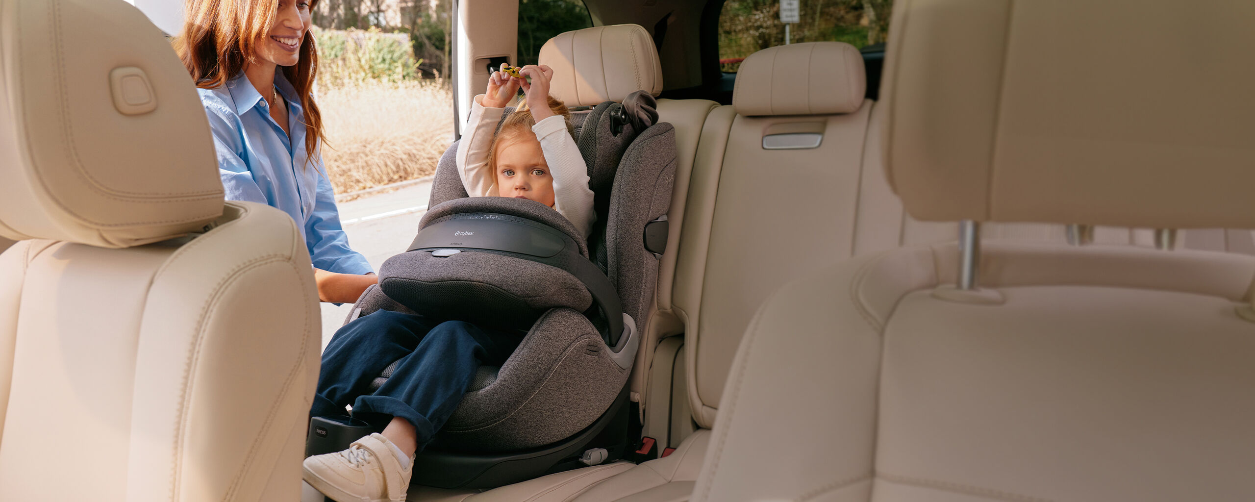 Mother buckling her child into the Anoris T2 i-Size Plus car seat with airbag in the car.