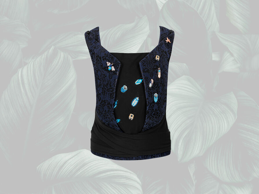 Black sleeveless top with blue embellishments and colourful insect embroidery on a grey leaf-patterned background.