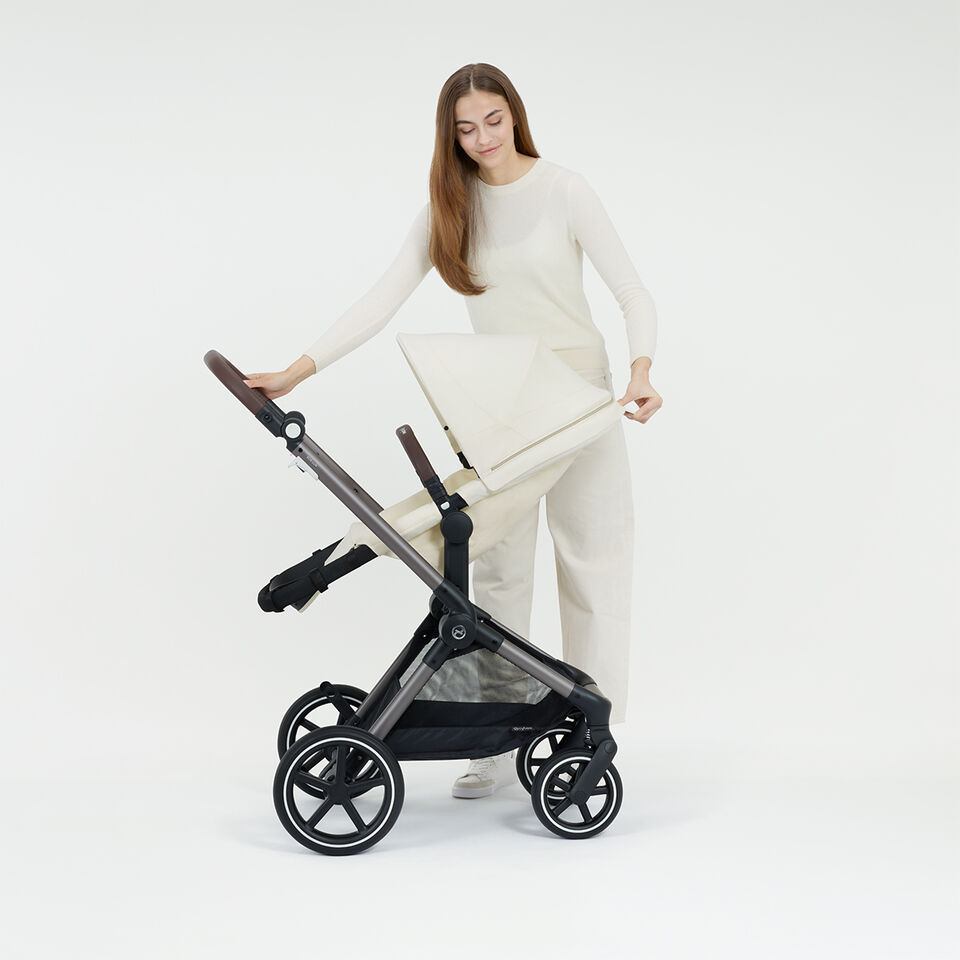 En kvinna f&auml;ller ner sin Eos Lux barnvagn till ett ergonomiskt fullt liggl&auml;ge.