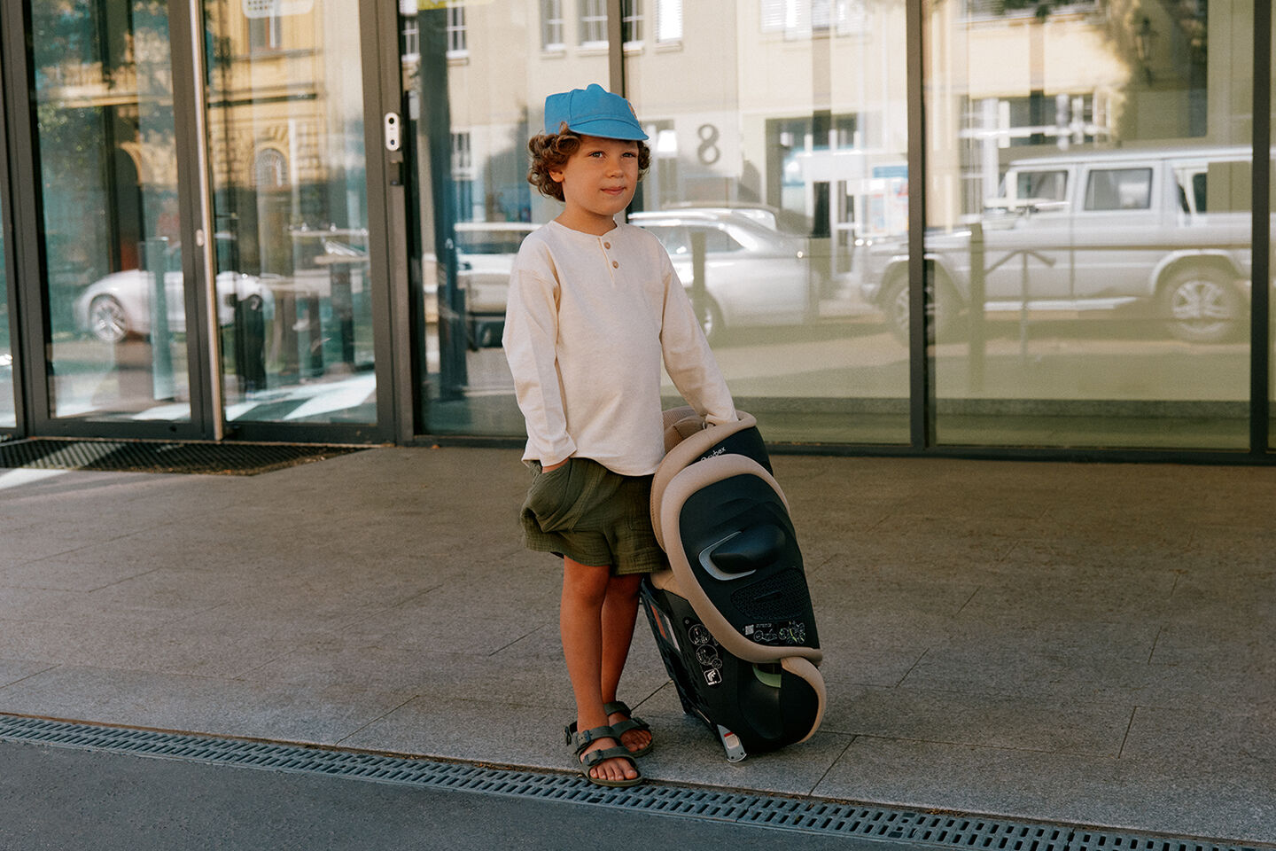 A child stands outside holding a Solution G2 travel car seat.