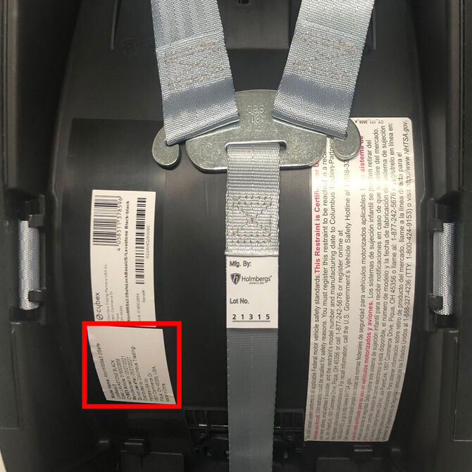 Labels on the back of a child car seat showing safety information and manufacturer details.