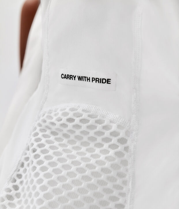 White bag with mesh fabric and a patch reading "Carry with Pride".