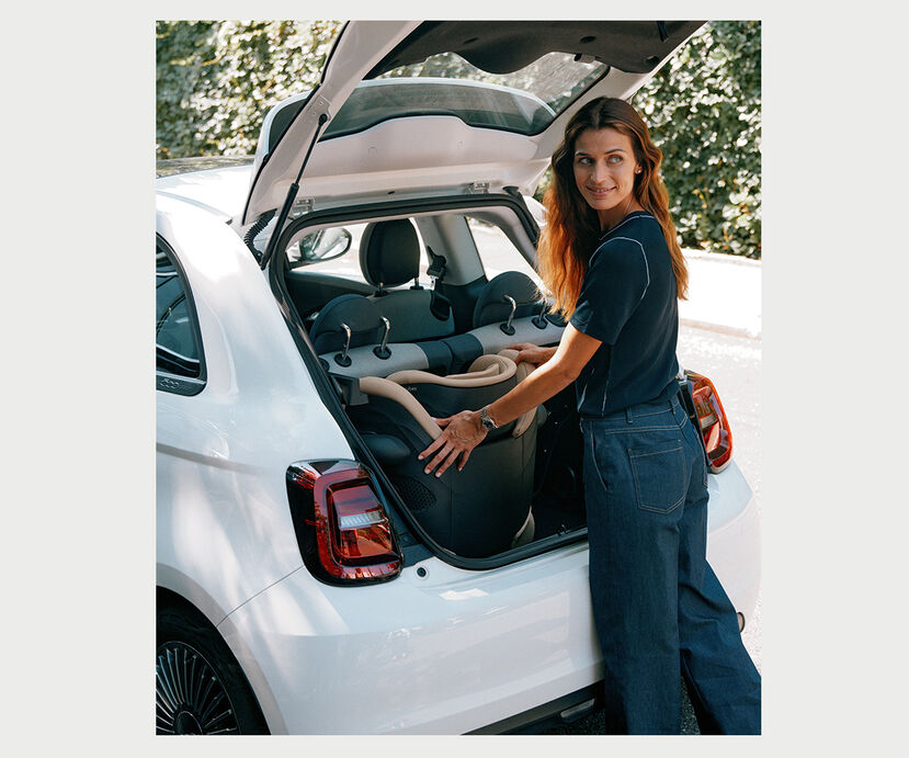 A woman placing a Solution G2 travel car seat into the boot of a white car.