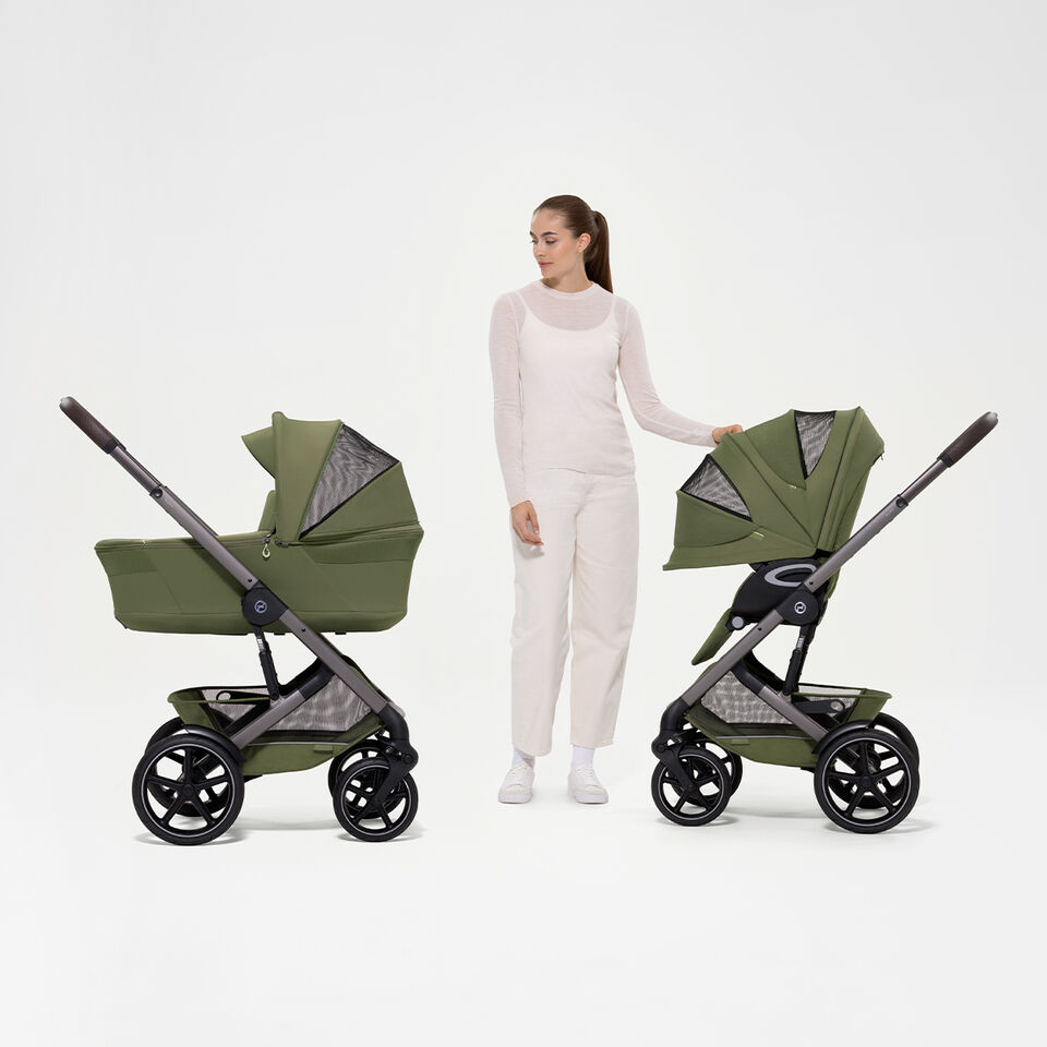 Eine Frau steht zwischen zwei Talos S Lux Kinderwagen, links mit Babywanne, rechts mit Sitzpaket.