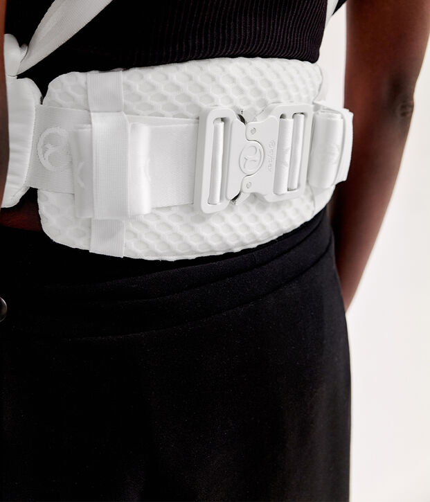 A white textured belt with a buckle around a person's waist.