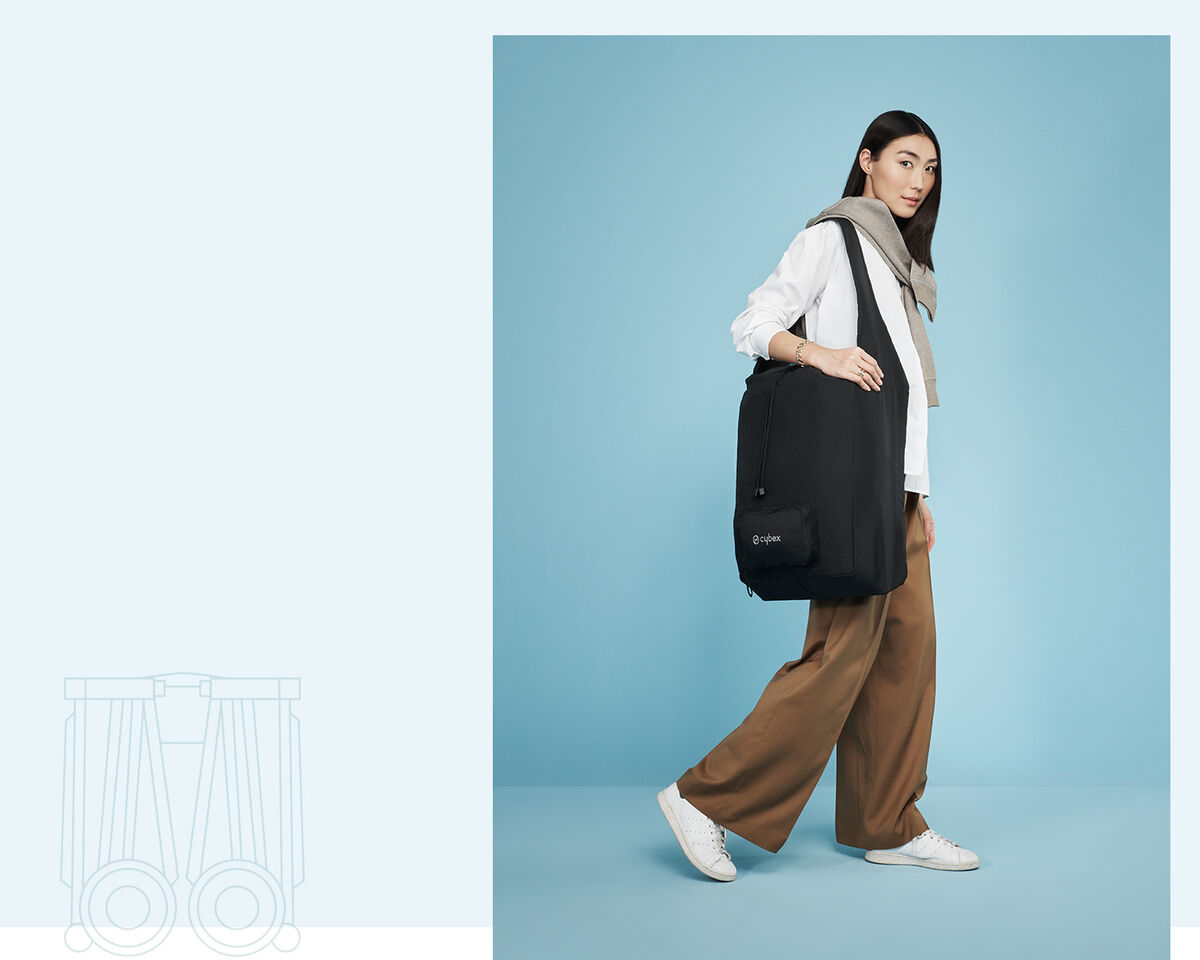 Woman carrying a Libelle smallest fold stroller in a black bag.