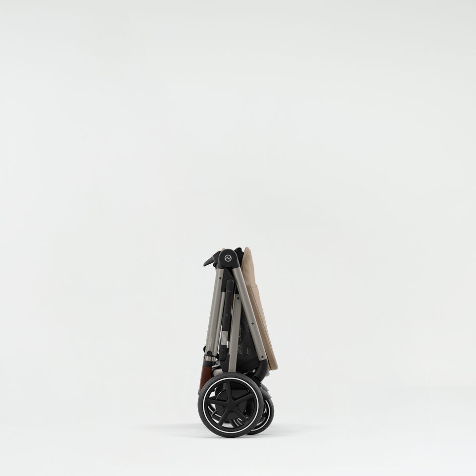 A woman standing next to a folded up Balios S Lux pushchair. 