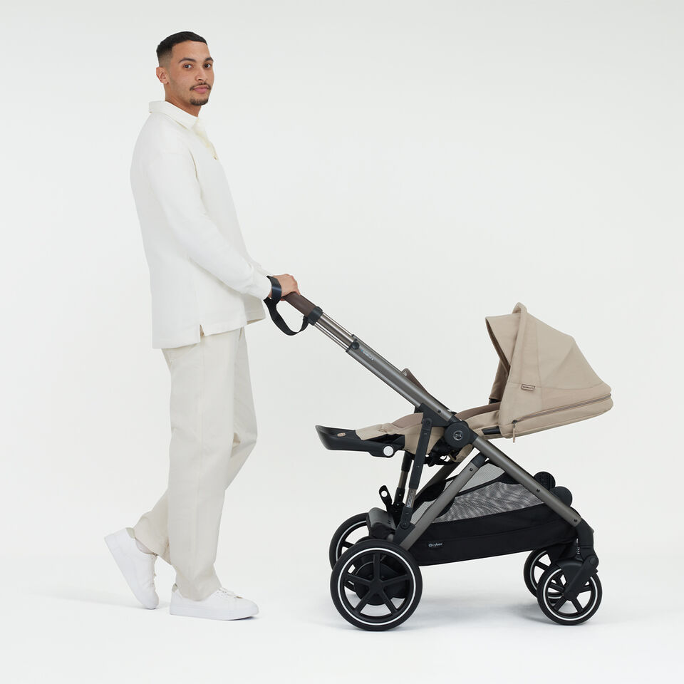 A woman pushing a Balios S Lux pushchair, the sun canopy completely down.
