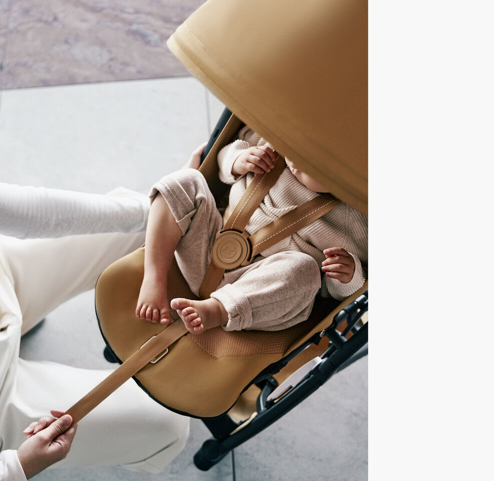 A woman pulling the one-pull harness of the Libelle with her child inside securely tight.