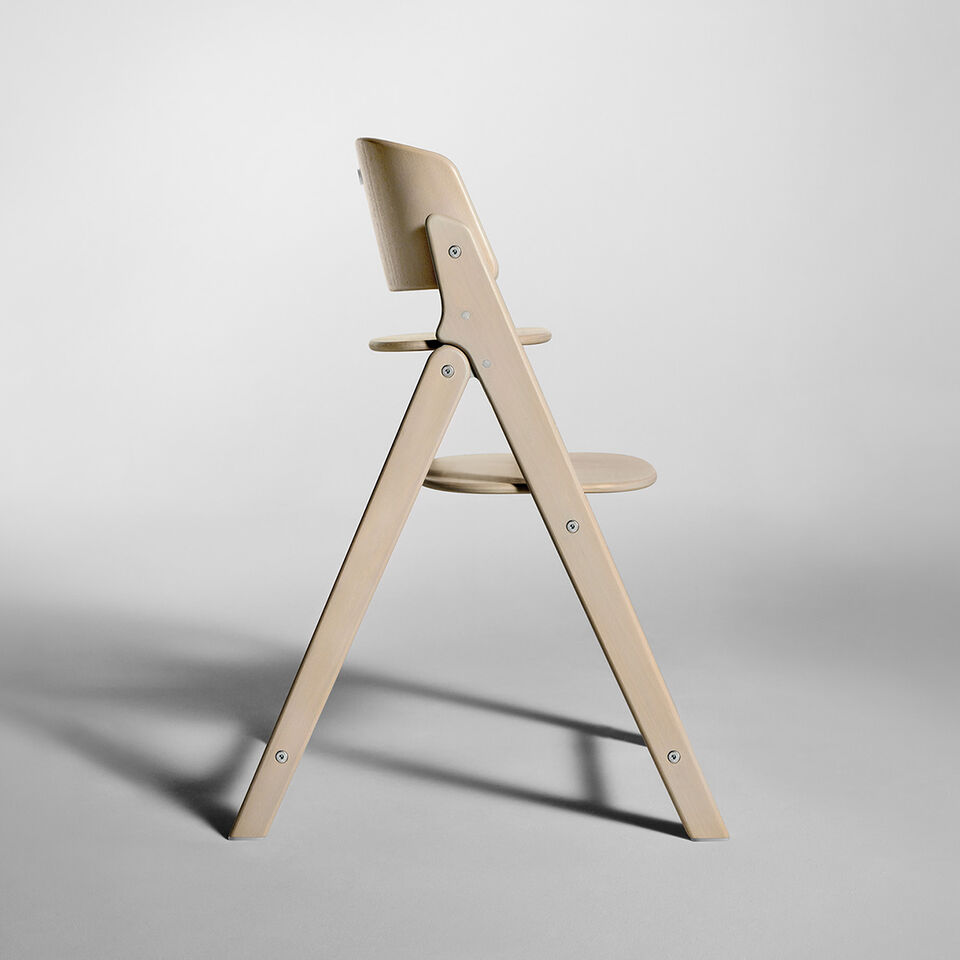 Side view of the Click and Fold high chair made of light wood on a grey background.