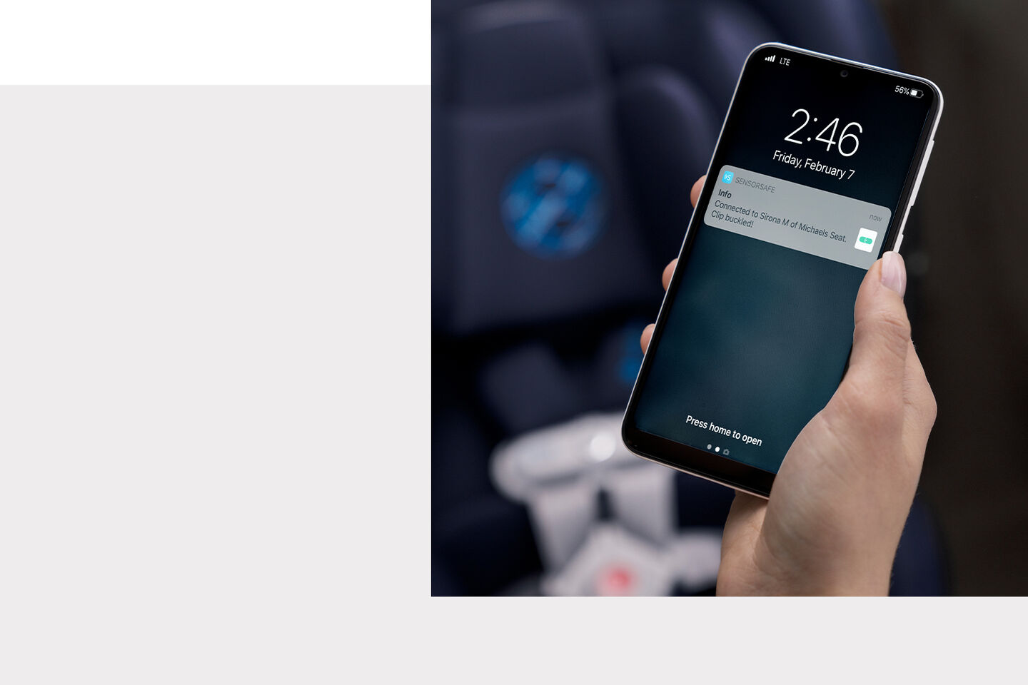 A hand holding a smartphone displaying a notification about connection to the Sirona S on a car seat.