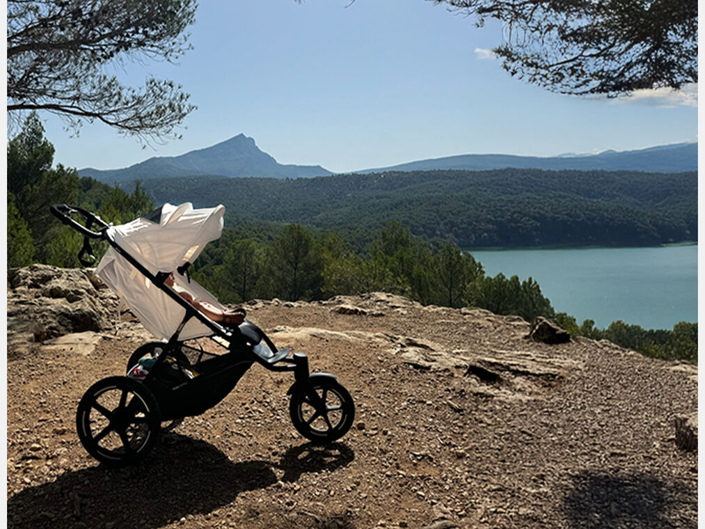 Sportovn&iacute; koč&aacute;rek Avi Spin stoj&iacute; na nerovn&eacute; zemi a&nbsp;za n&iacute;m je vidět jezero a&nbsp;lesy.
