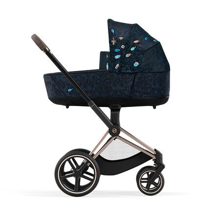 Pram with dark blue pattern and colourful embroidery on the hood, side view.