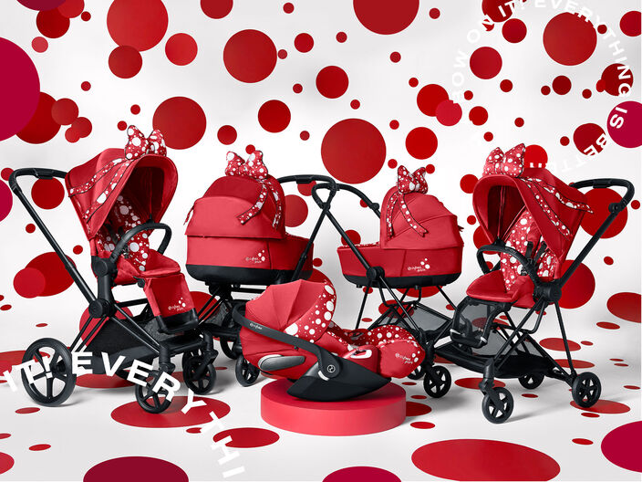 Bright red strollers with white polka dots and bows, set against a background of red circles.