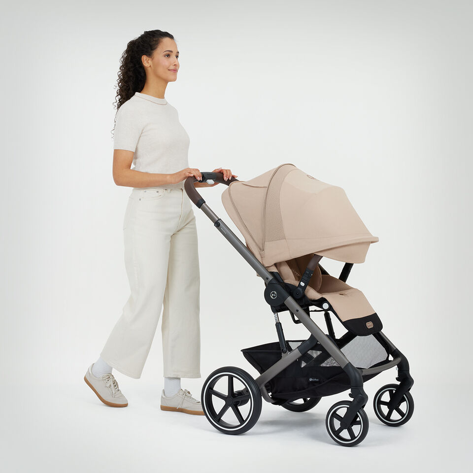 A woman pushing a Balios S Lux stroller, the sun canopy completely down.