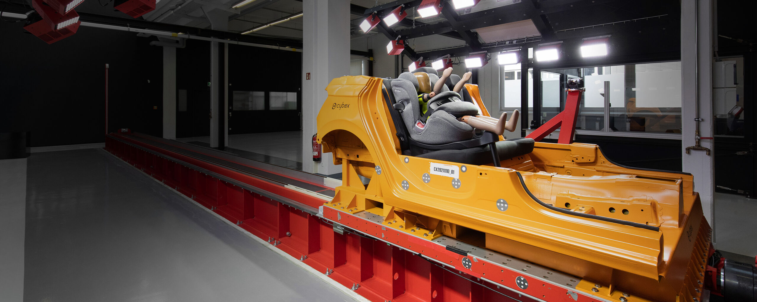 A crash test dummy seated in a Cybex car seat on a test track in a laboratory.