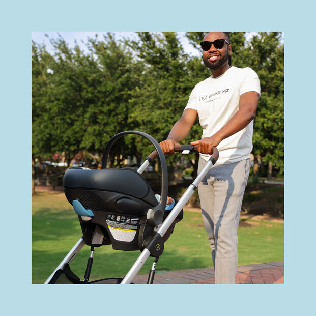 A man pushes a compact jogging stroller, the Aton G Swivel, in the park.