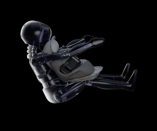 Ein transparentes Crash-Test-Dummy-Modell, das einen Kindersitz h&auml;lt, vor einem schwarzen Hintergrund.