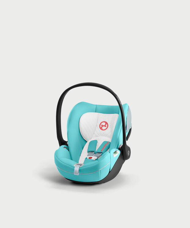 by Jeremy Scott Wings car seat in turquoise and white with a black handle on a white background.