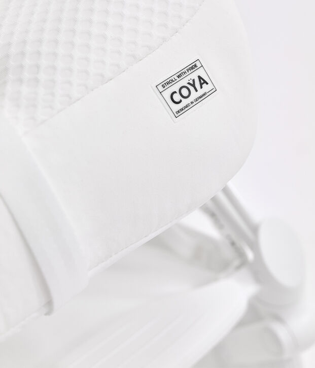 A white stroller with a label reading "Stroll with Pride, Coya, Designed in Germany."