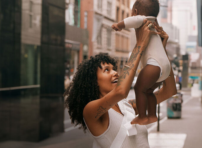 A woman lifting her child in the air, smiling at them.