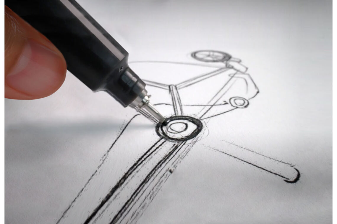 A close-up of a hand drawing a rough sketch of a pushchair frame on a piece of paper with a black pen.