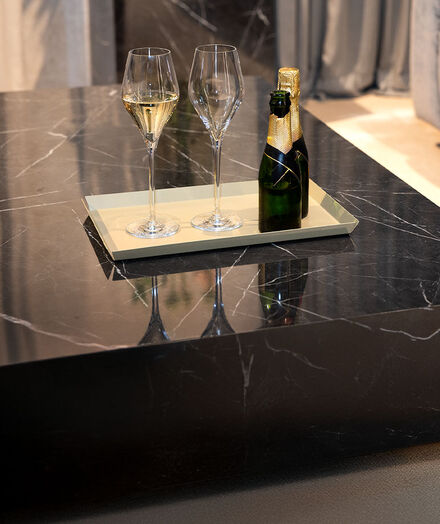A black marble table with a tray on it. On the tray, there are two bottles and two glasses of champagne.