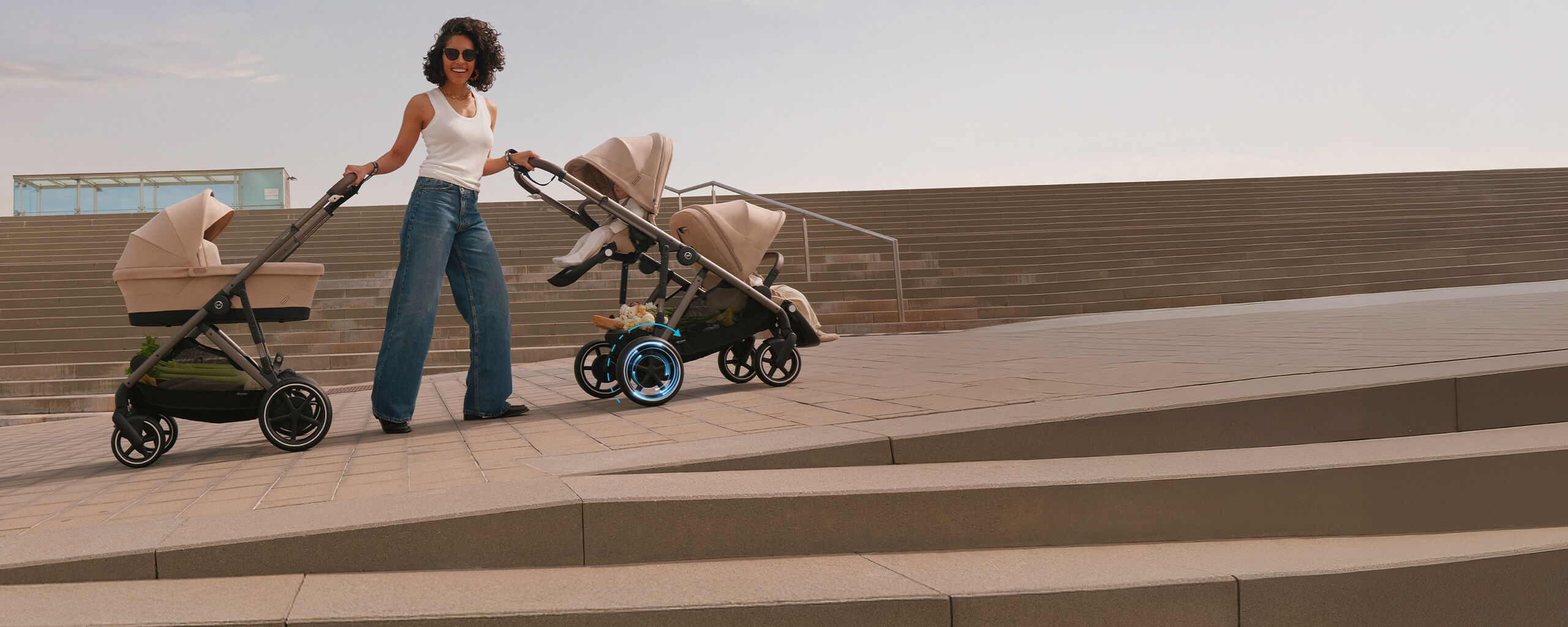 A mother laughing into the camera, holding two e-Gazelle S' with each hand as she's standing on an incline, showcasing the e-power the e-Gazelle S has.