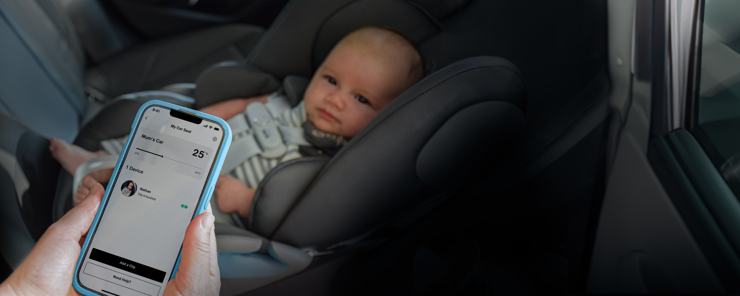 Un b&eacute;b&eacute; est assis dans un si&egrave;ge auto tandis qu'une personne tient un smartphone affichant une application pour surveiller la temp&eacute;rature du si&egrave;ge.