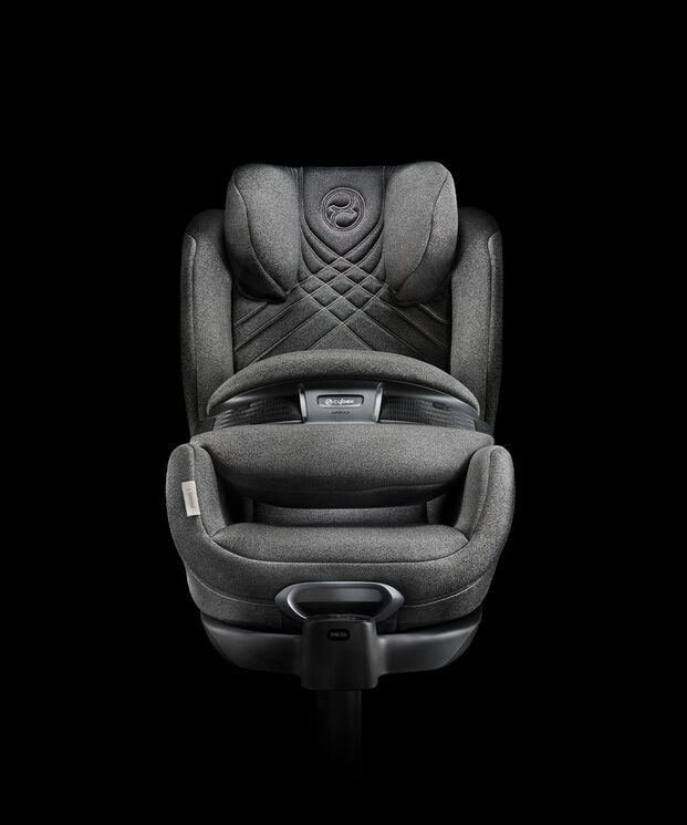 A grey, luxurious child car seat with padded design and safety features on a black background.