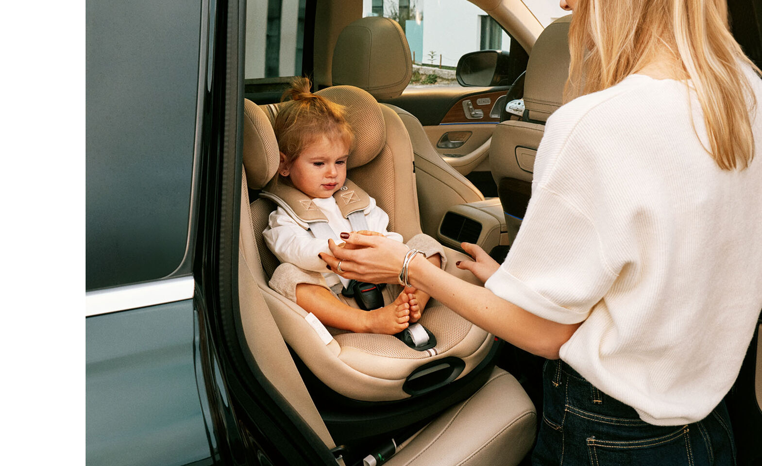 A woman taking her daughter out of the car, the Sirona G i-Size that the little girl is sitting in is turned towards the door.
