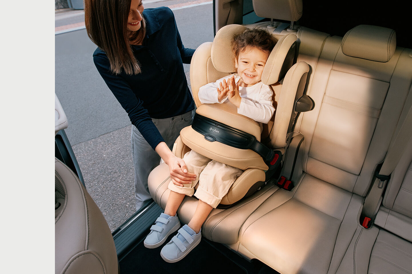 Pallas G2 growing child seat, a smiling child sits in the car seat while an adult holds their hand