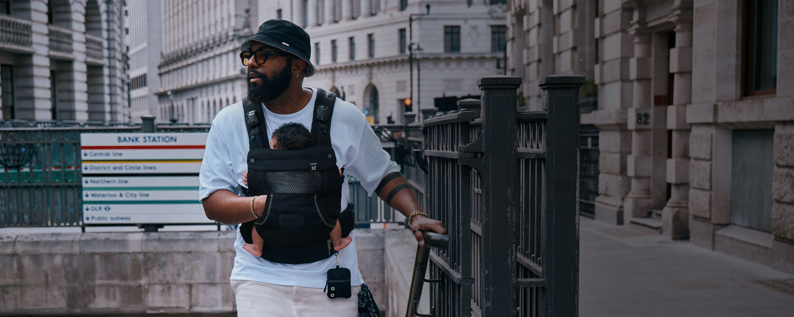 A man carrying his baby in a Laya baby carrier with his hand in the the kangaroo pockets the Laya baby carrier has to offer.
