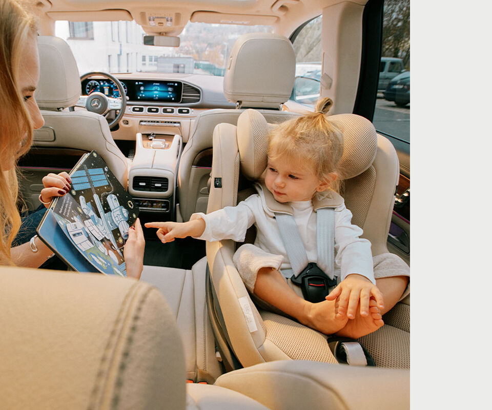 Un enfant pointe du doigt un livre d&rsquo;images que sa m&egrave;re tient, assis &agrave; l&rsquo;arri&egrave;re de la voiture dans un si&egrave;ge auto Sirona G i-Size.