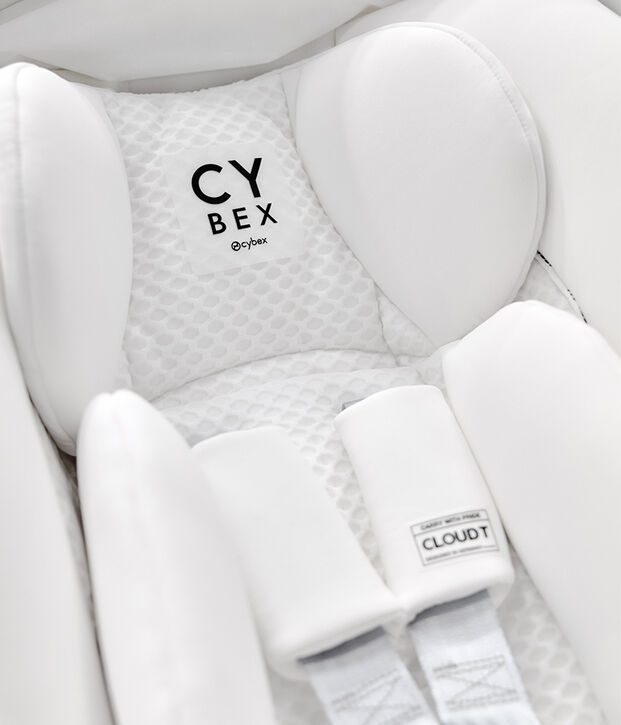 Un seggiolino auto Cybex bianco con un&rsquo;imbottitura morbida e un logo sullo schienale.