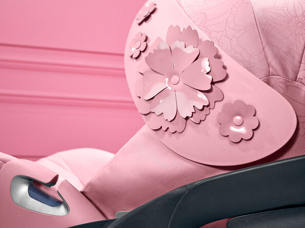 CYBEX Simply Flowers bilbarnstol i rosa med dekorativa blomanpassningar.